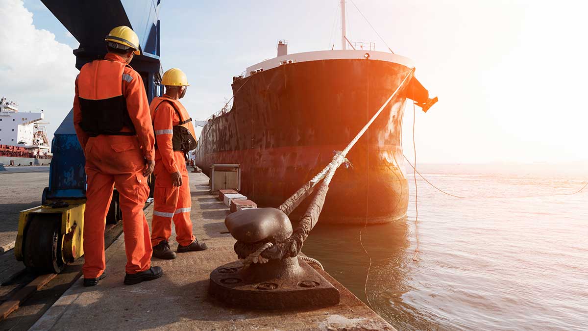 Workers at a quayside, waiting for cargo ship to dock