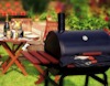 BBQ in the foreground with a garden table behind set with wine glasses and champagne view 1