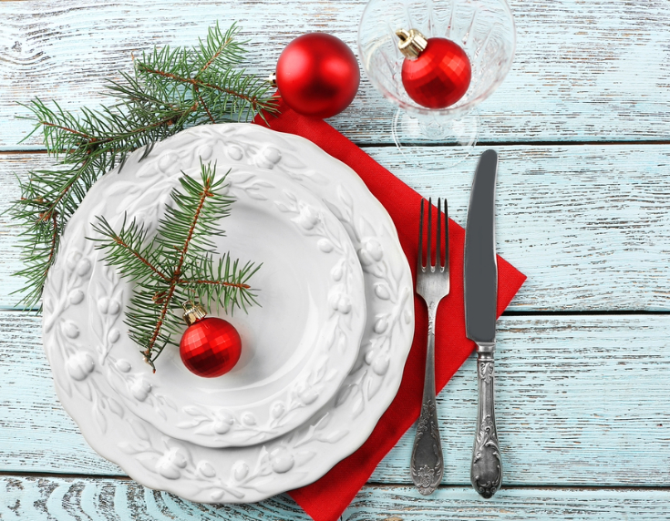 Festive place setting of two stacked white plates and cutlery with red bauble decoration