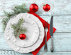 Festive place setting of two stacked white plates and cutlery with red bauble decoration