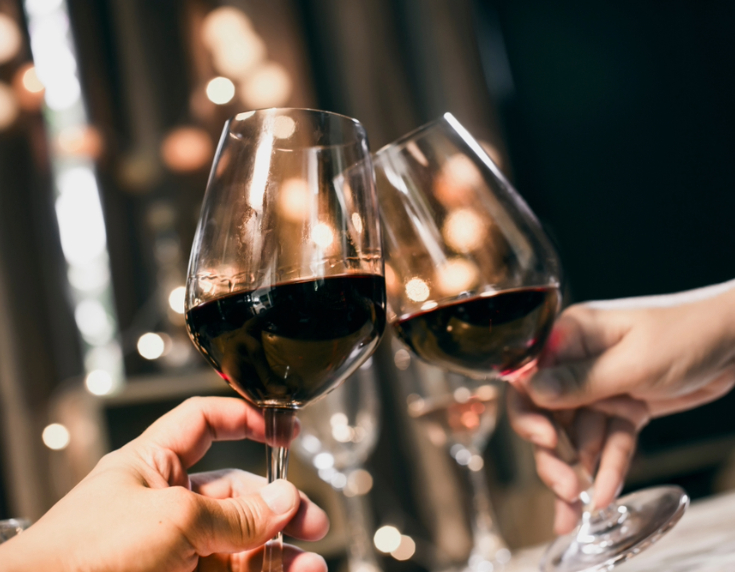 Two glasses of red wine being held up in a toast