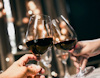 Two glasses of red wine being held up in a toast